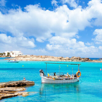 Els Pujols beach in Formentera with traditional fishing boat in summer day